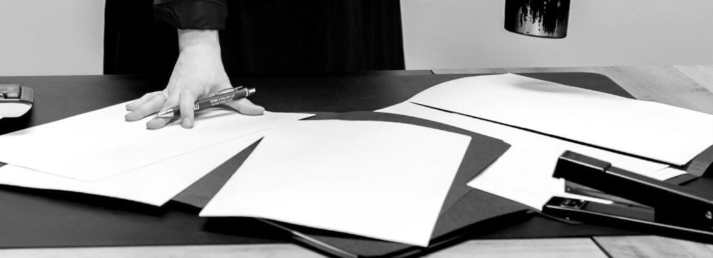 Legal professional drafting agreement documents on a desk.