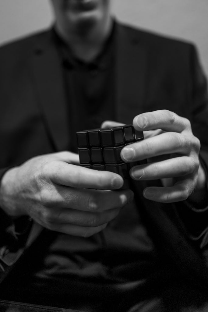 Business person solving a Rubik's Cube, symbolizing strategic problem-solving.